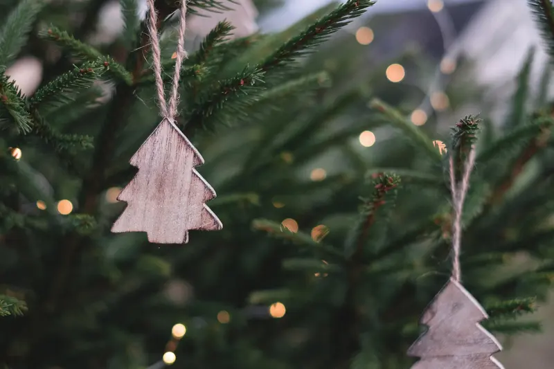 Simple wooden tree-shaped decorations hanging on a real Christmas tree