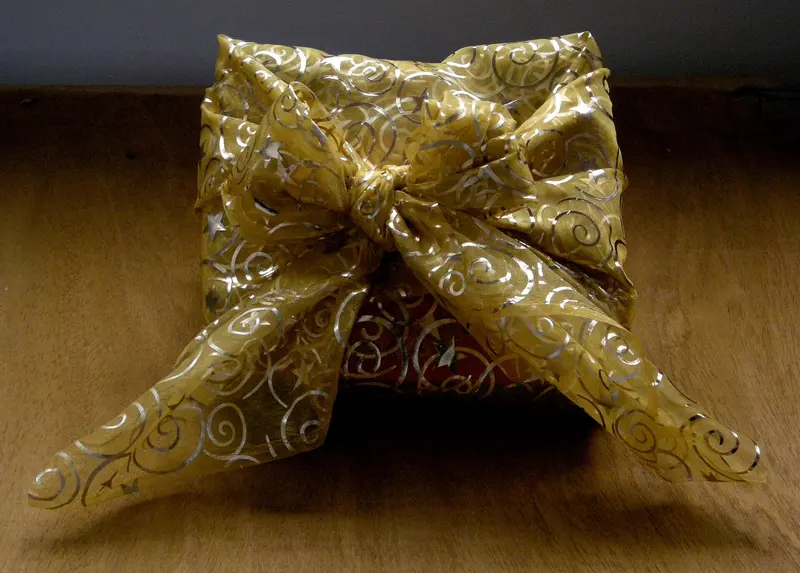 A present wrapped in gold fabric tied in a bow
