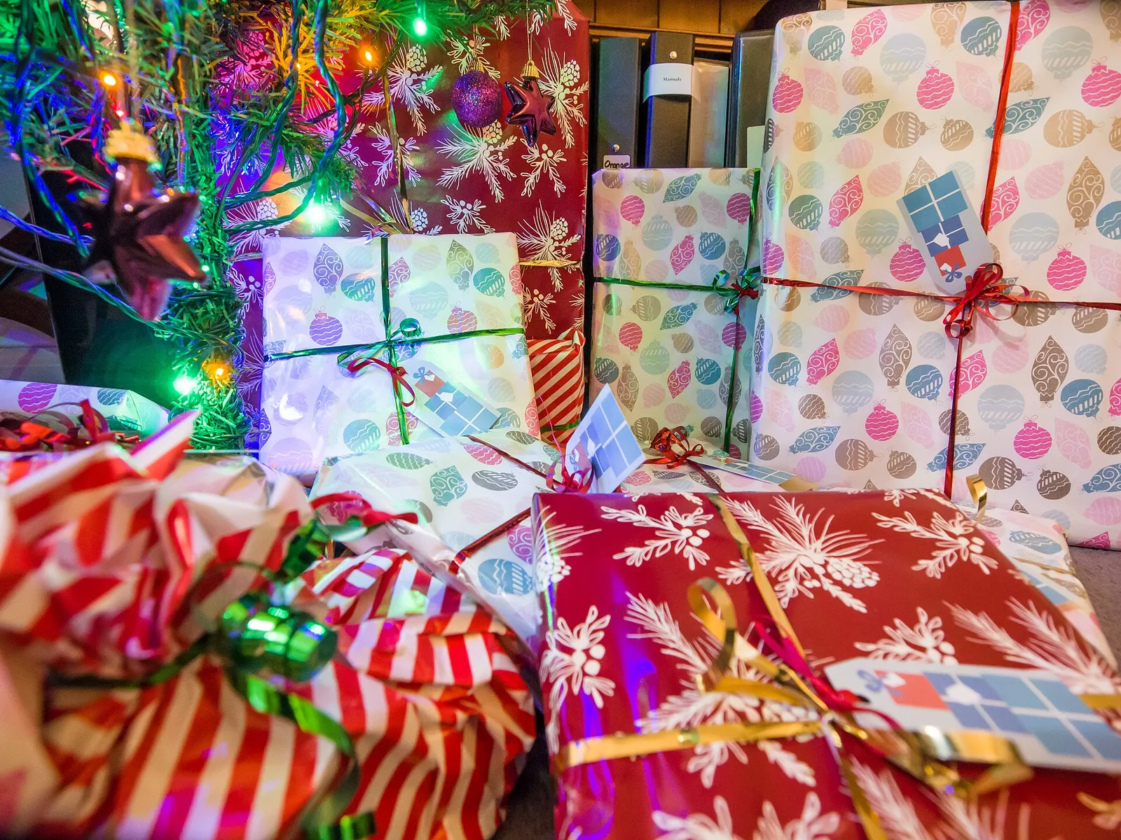 Brightly wrapped Christmas presents piled under a decorated tree