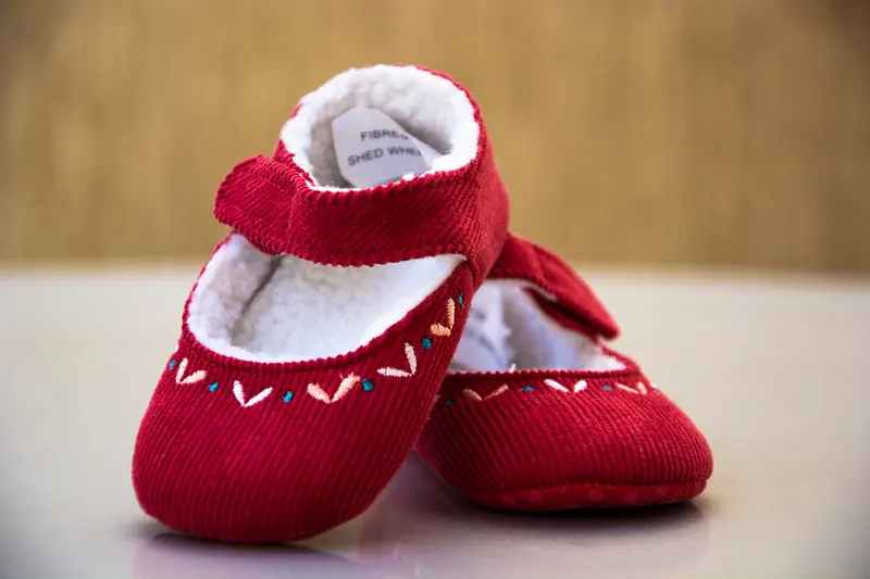 A pair of tiny red baby shoes with white lining