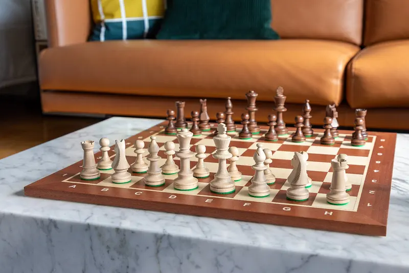 A wooden chess set laid out ready to play on a marble table