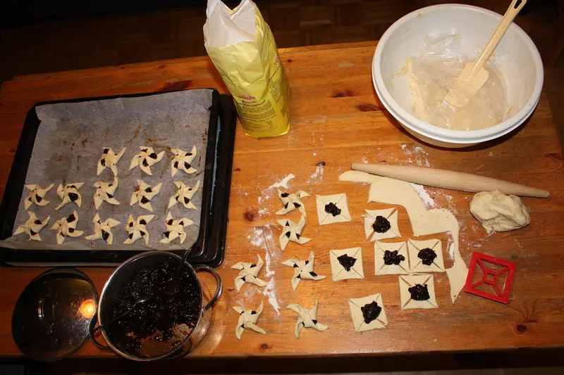 A baking table with rolled-out pastry, a rolling pin, a tray of star-shaped pastries and a mixing bowl