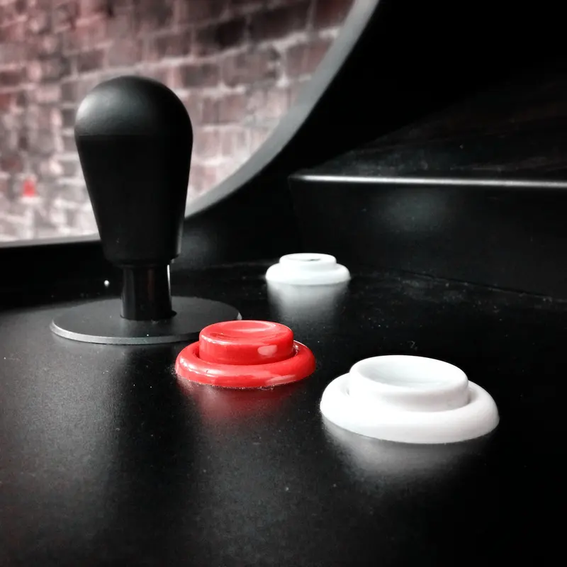 A black arcade joystick with red and white buttons