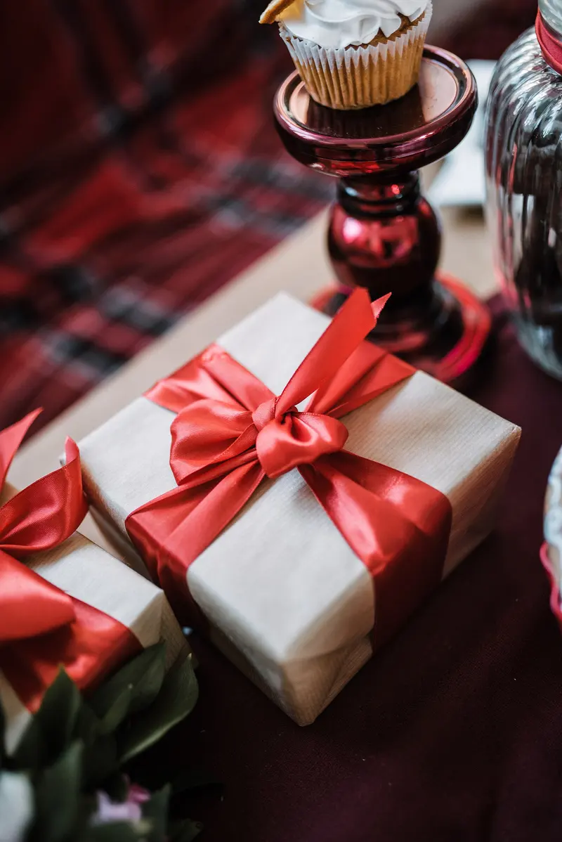 A brown gift box tied with a red satin ribbon and bow