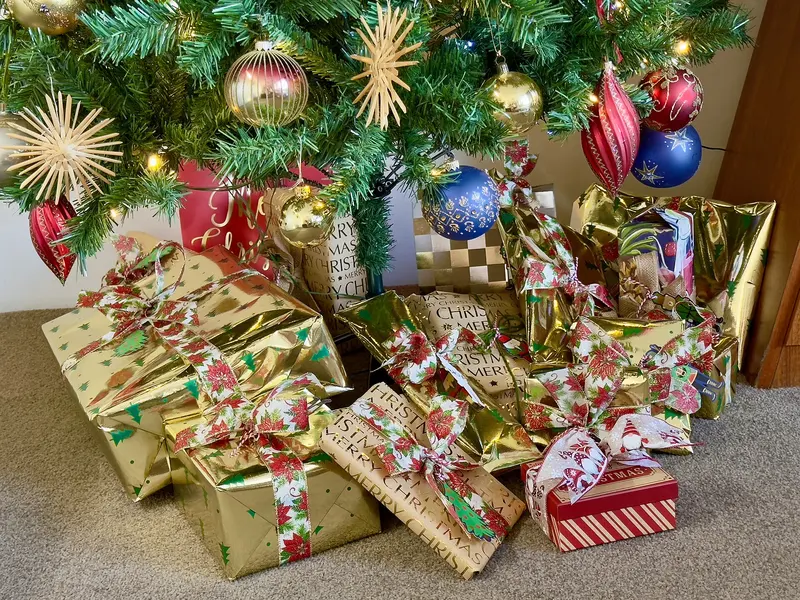 Gold and red wrapped presents piled under a decorated Christmas tree