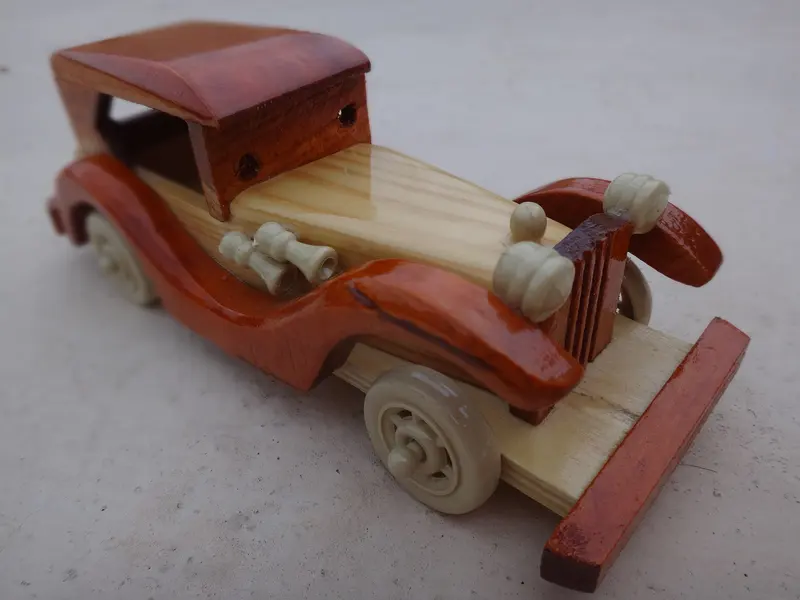 A handmade wooden toy vintage car with spoked wheels