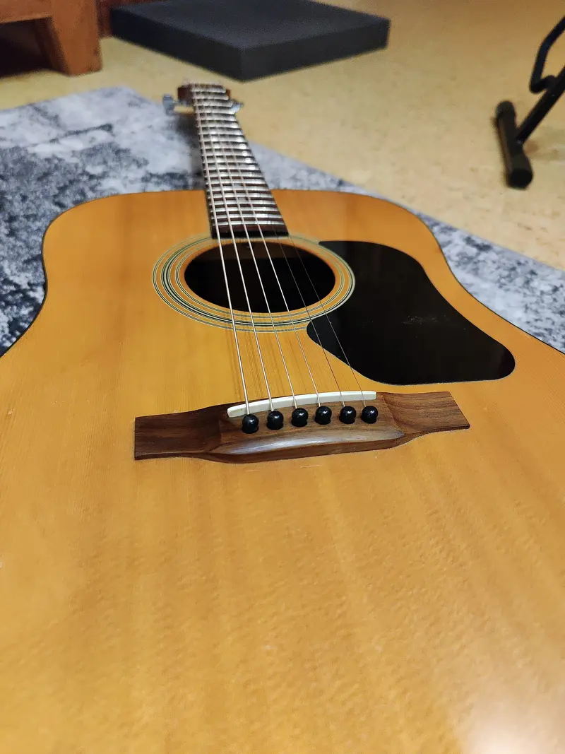 The body and strings of an acoustic guitar lying on a rug