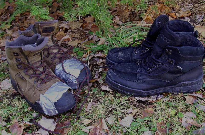 Two pairs of well-worn walking boots on fallen leaves