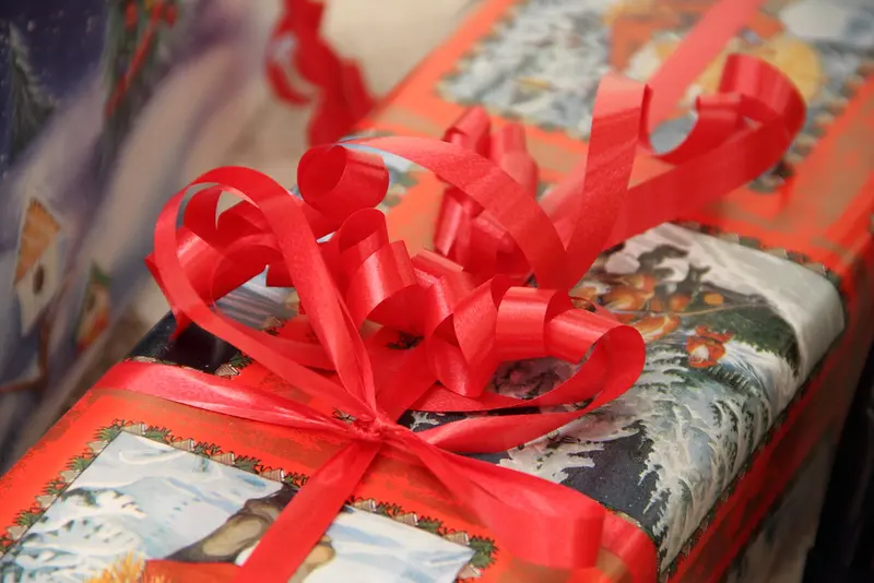 A present in Christmas wrapping paper tied with a big red curled-ribbon bow