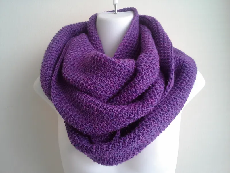 A purple hand-knitted wool infinity scarf on a dress form